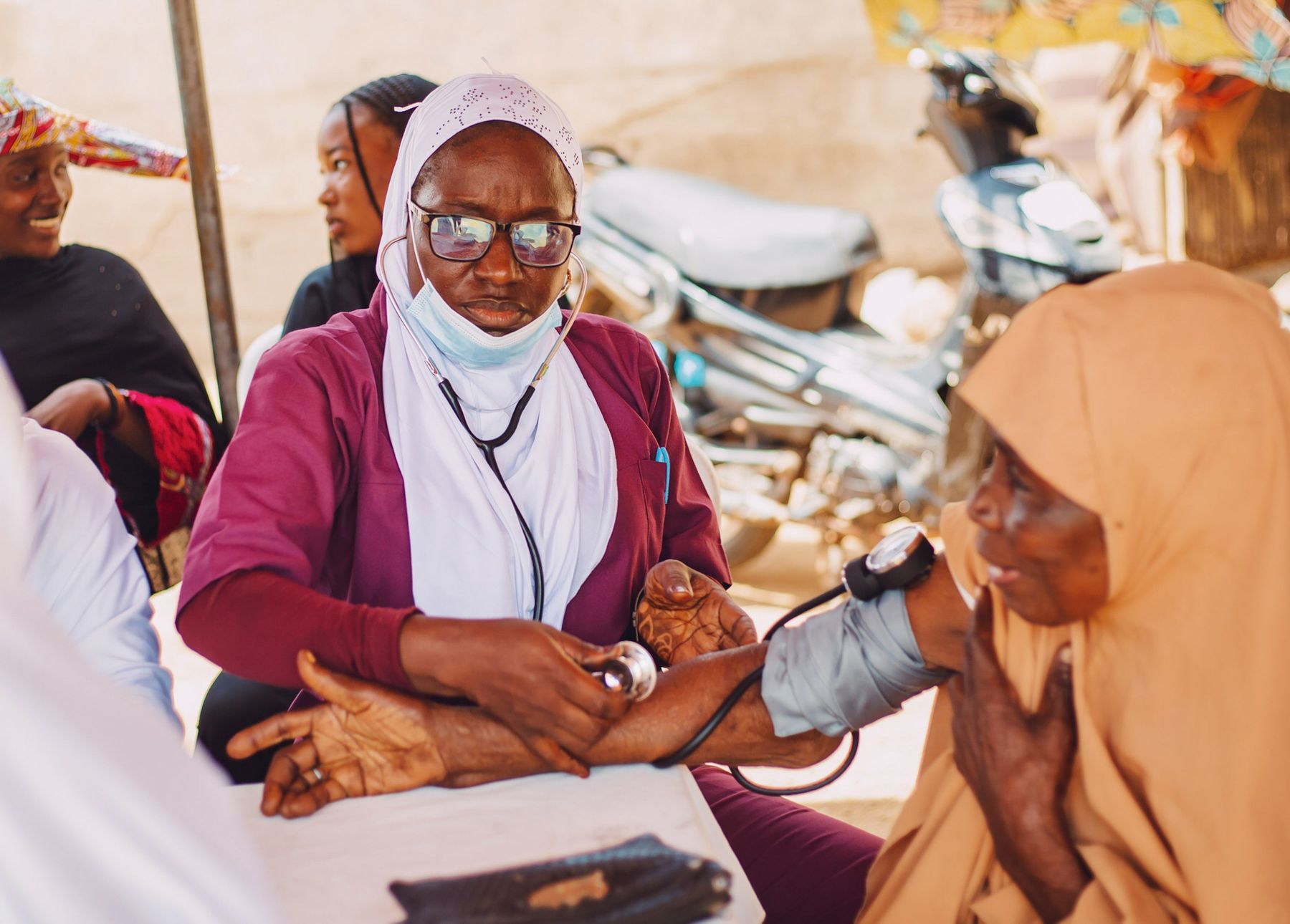 Healthcare worker checking a community member's blood pressure
