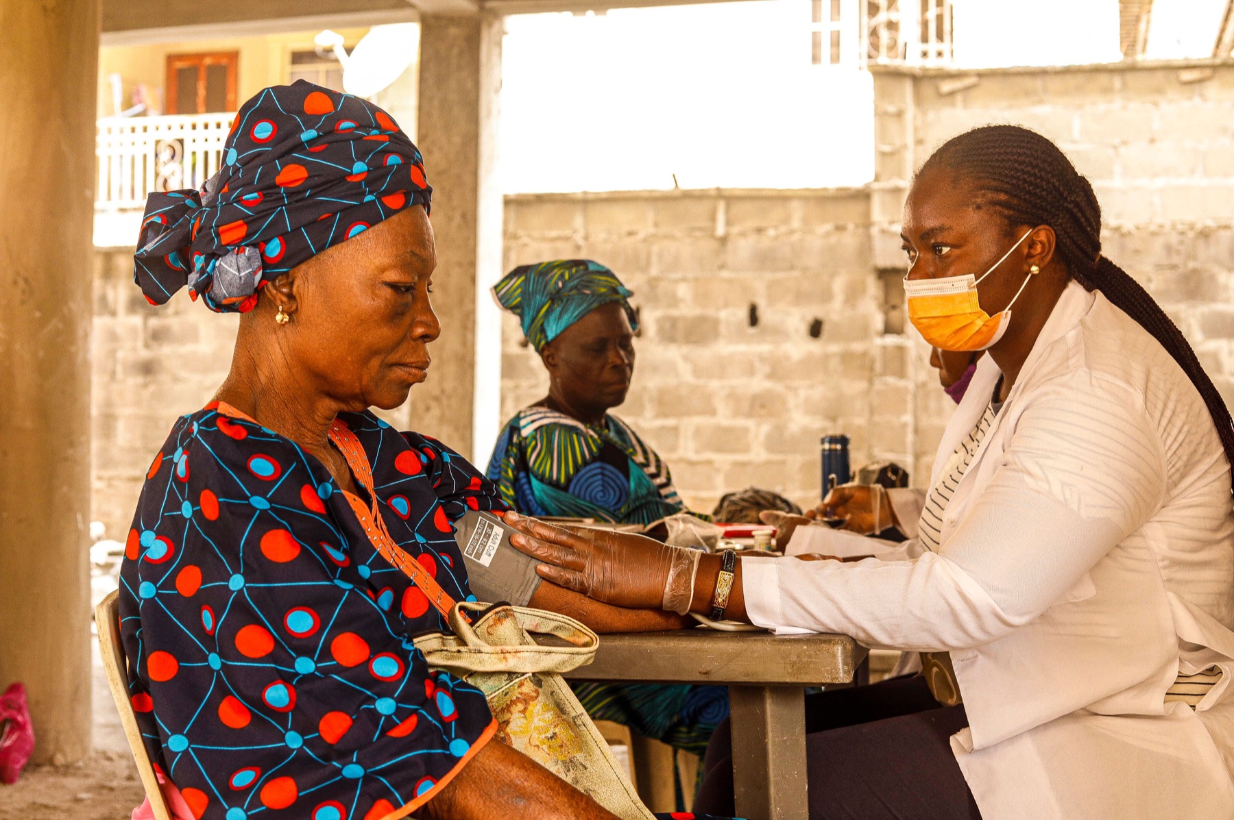 A healthcare professional checking an older woman's blood pressure at a community health outreach